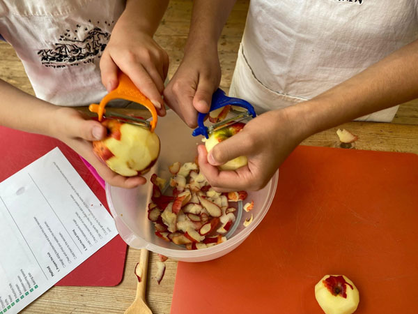 Children's hands peeling apples ionto a bowl
