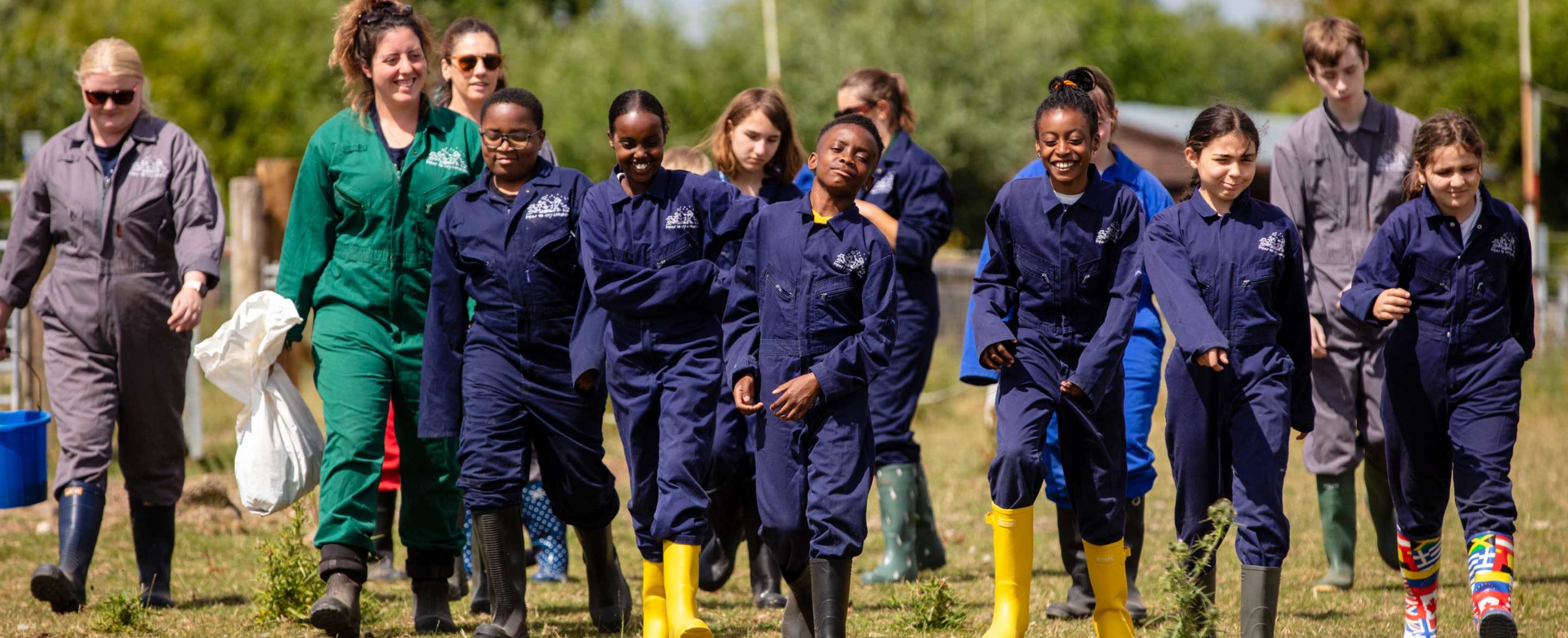 Young people in Farms for City Children overalls walking in a line
