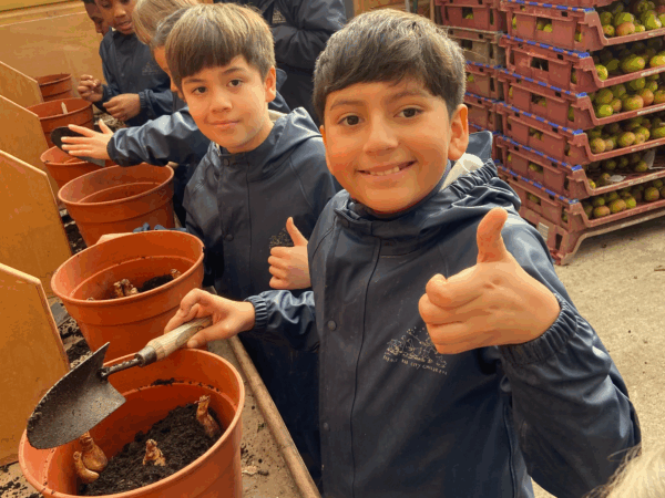 Children in Farms for City Children overalls planting daffodil bulbs at Nethercott House