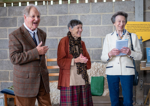 HRH The Princess Royal with a copy of Down Burrow Lane., standing with Clare and Michael Morpurgo. All three are smiling.