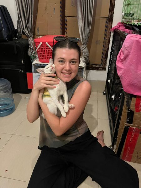 Lou's daughter sat smiling holding a white cat 