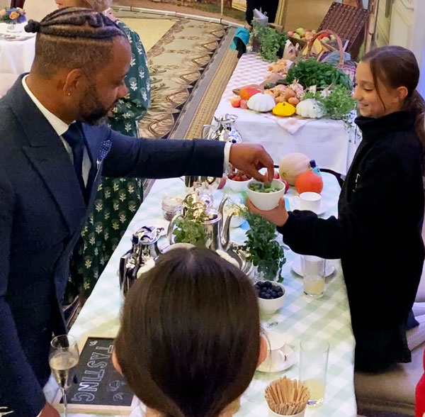 Farms for City Children ambassador JB Gill tasting farm produce offered to him by a young person