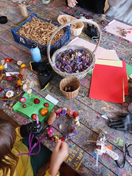 A shot from above of a wooden table, dried flowers and craft materials