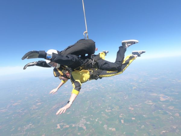 A lady in neon skydive kit, tandom skydiving in blue skies