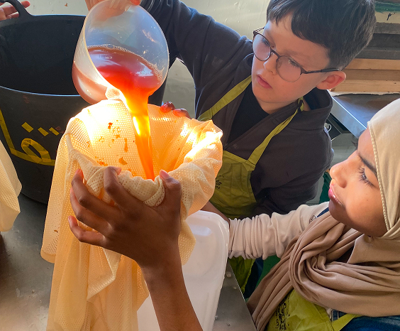 School children in Farms for City Children aprons filtering apple juice